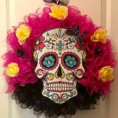 a wreath decorated with flowers and a sugar skull