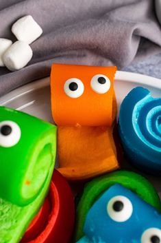 some colorful candies with googly eyes are on a plate