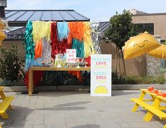 a yellow picnic table with some decorations on it and balloons hanging from the ceiling in the background