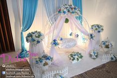 a white and blue wedding set up with flowers on the bed, veils and chairs