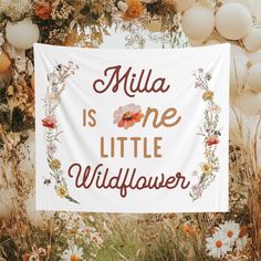 a white sign that says, milla is one little wildflower with flowers around it