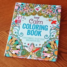 the calm coloring book sits on a wooden table with it's cover pulled down