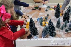 children are playing with toy trees on the table