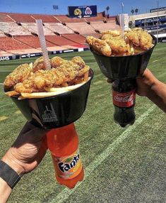 two buckets filled with fried chicken sitting on top of a field next to each other