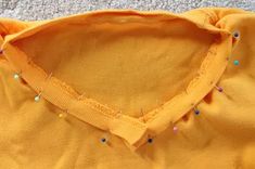 a yellow shirt with colorful pins on the collar is laying on top of a carpet