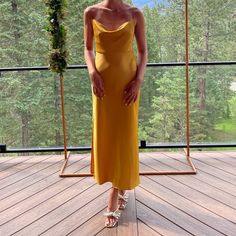 a woman in a yellow dress standing on a deck