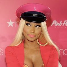 a woman with long blonde hair wearing a pink top and large hat on her head