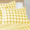 a bed topped with yellow and white checkered pillows