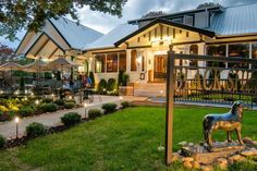 a statue of a horse stands in front of a house with lights on the porch