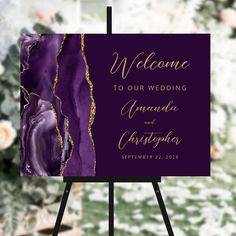 a purple and gold wedding welcome card on an easel