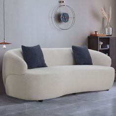 a white couch sitting in a living room next to a clock on the wall above it