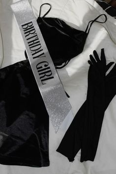 two black gloves and a silver ribbon on a bed