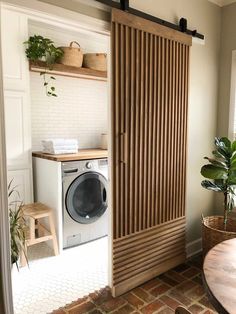 a laundry room with a washer and dryer in the corner, next to a potted plant