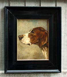 a painting of a brown and white dog in a black frame