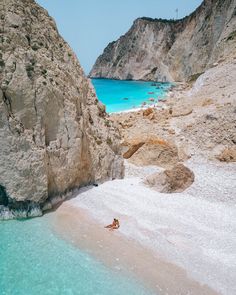 a person laying on the beach next to some rocks