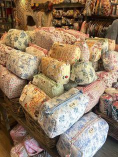 a large pile of pillows sitting on top of a wooden floor in front of a store