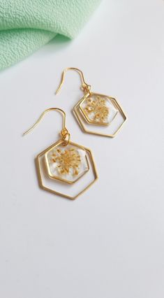 gold earrings with white and yellow flowers on them