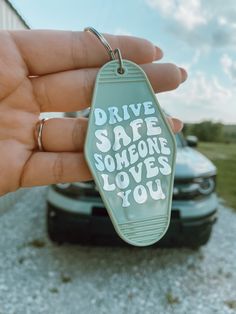 someone is holding up a keychain with the words drive safe someone loves you on it