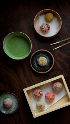 there are many small desserts in bowls on the table with chopsticks next to them