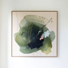 an abstract painting hangs on the wall above a chair in a room with white walls