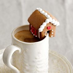 there is a small gingerbread house in a mug on top of a saucer