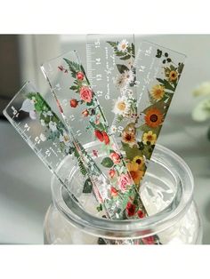 four rulers are in a jar with flowers on it