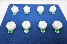 several white plastic knobs with green letters on a blue carpeted flooring area