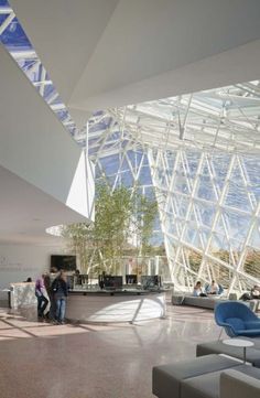 people are standing in the lobby of an airport with large glass walls and ceilinging