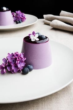 there is a purple cake with flowers on the top and blueberries on the bottom