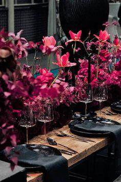 the table is set up with wine glasses and flowers in vases on each side