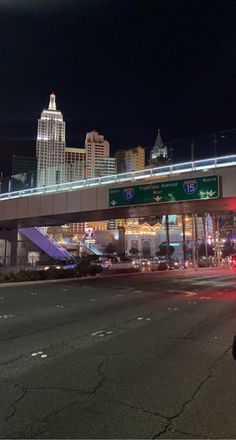 a city street at night with traffic lights and an overpass above the road that is lit up