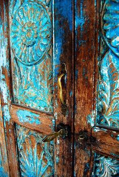 an old wooden door with blue paint and ornate carvings on it's side panel