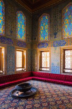 an ornate room with stained glass windows and red couches in the middle of it