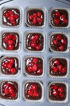 chocolate cupcakes with cherries in a muffin tin ready to be baked