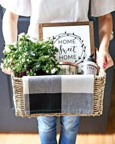 a person holding a basket with plants in it and a sign that says home sweet home