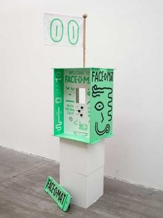 a green and white pay phone sitting on top of a cement floor next to a sign