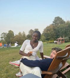 a woman sitting on a chair next to a man who is holding a drink in his hand