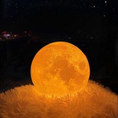 a large yellow moon lamp sitting on top of a fluffy white blanket next to a window