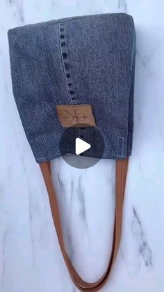 a pair of jeans hanging from a hook on a marble counter top with a leather cord attached to it