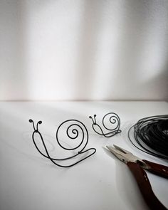 a pair of scissors sitting next to a wire sculpture with the word snail on it