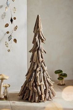 a small wooden christmas tree sitting next to mushrooms and other decorations on the floor in front of a wall