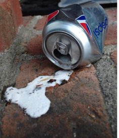 a can of soda sitting on top of a brick wall