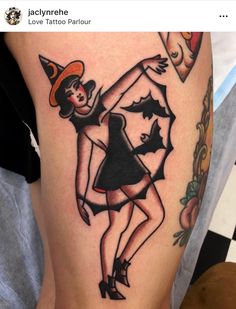 a woman wearing a witches hat and black dress on her thigh, with the word love tattoo parlou