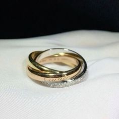 two gold wedding rings sitting on top of each other in front of a white cloth