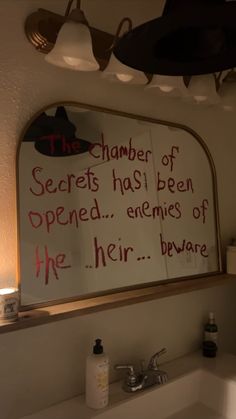 a bathroom sink with a mirror above it that says the chamber of secrets has been opened