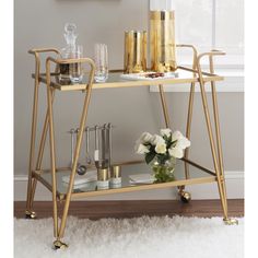 a gold bar cart with drinks on it in front of a white rug and window