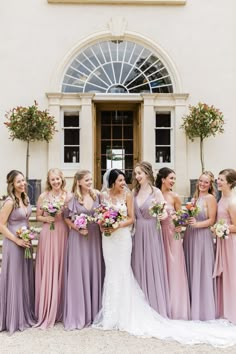 a group of women standing next to each other in front of a building with flowers