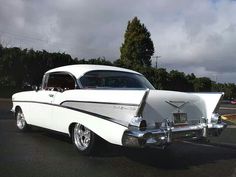 an old white car is parked on the side of the road