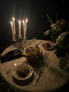 a table with candles and food on it in the middle of some sort of night