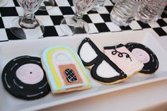 decorated cookies in the shape of music instruments on a table with wine glasses and checkered tablecloth